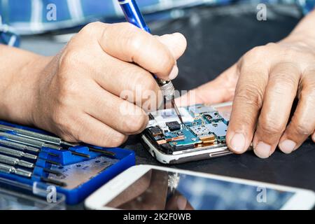 Technician repairing inside of mobile phone by soldering iron. Integrated Circuit. the concept of data, hardware, technology. Stock Photo