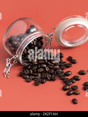 Roasted Coffee beans in a glass jar on pink background close up Stock Photo