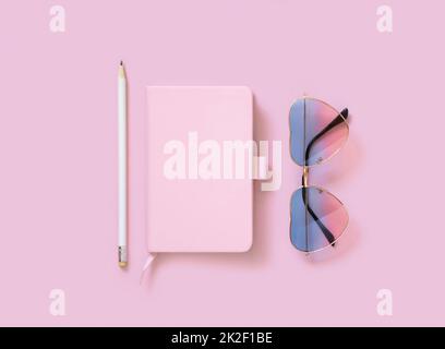 Hardcover textbook, heart sunglases and pensil on pink, mockup. Stock Photo