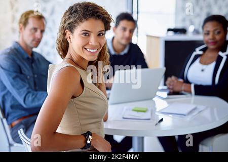I work with the best. Portrait of a young businesswoman with colleagues in the background. Stock Photo