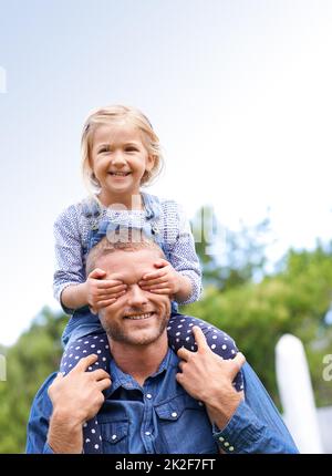 In control from an early age. Shot of a little girl on her daddys shoulders covering his eyes with her hands. Stock Photo
