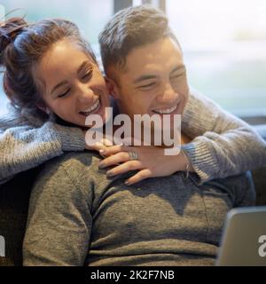 Sharing both love and laughter. Shot of an affectionate young couple surfing the net while relaxing on the sofa at home. Stock Photo