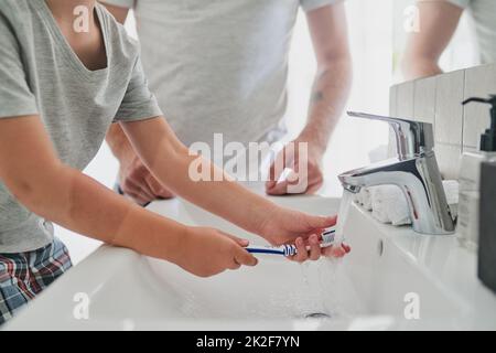 Good habits start every morning. Closeup shot of an unrecognizable little boy brushing his teeth with his father in the bathroom at home. Stock Photo
