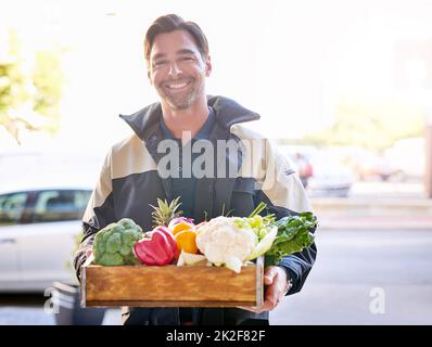 Theyre grown with love and delivered with care. Portrait of a courier making a grocery delivery. Stock Photo