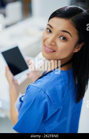 Its the only assistant I need. High angle portrait of an attractive young female nurse using a tablet while standing in the hospital. Stock Photo
