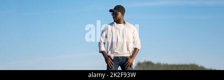 African American man in a cap and sunglasses stands on the street Stock Photo