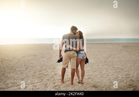 Romantic seaside strolls at sundown. Shot of a young couple spending a romantic day at the beach. Stock Photo