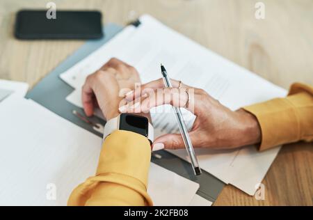 Time management is important in the workplace to get higher productivity. Closeup shot of an unrecognisable businesswoman checking her wristwatch while writing notes in an office. Stock Photo