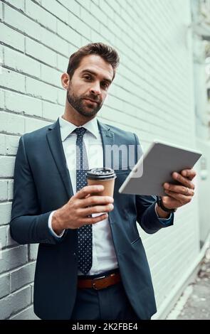 Handling all his business matters on the move. Portrait of a handsome young businessman using a digital tablet outdoors. Stock Photo