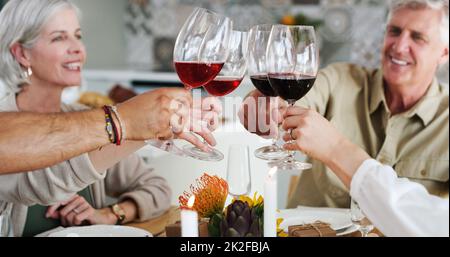 Heres to friends who feel like family. Shot of two happy couples sitting down for lunch and toasting with wine glasses at home. Stock Photo