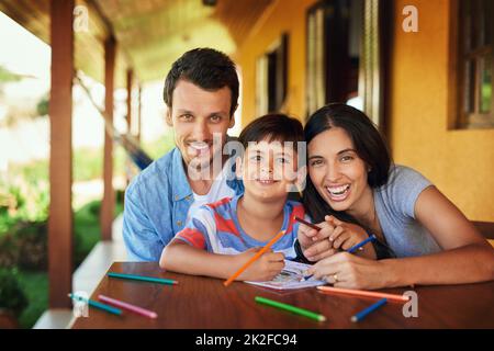 We make time to share special moments together. Portrait of a couple and their son coloring in together outdoors. Stock Photo