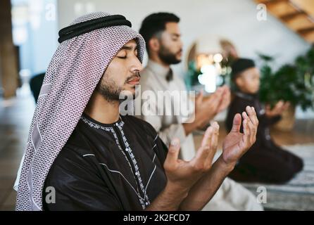 Prayer with a thankful heart. Shot of a group of muslim male family members praying together. Stock Photo