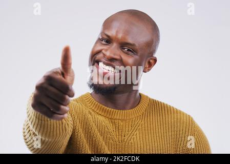 Im happy to agree. Studio portrait of a handsome young man giving a thumbs up against a grey background. Stock Photo