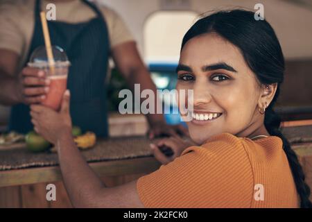 This is my favourite food truck. Shot of a woman buying and drinking a smoothie from a food truck. Stock Photo