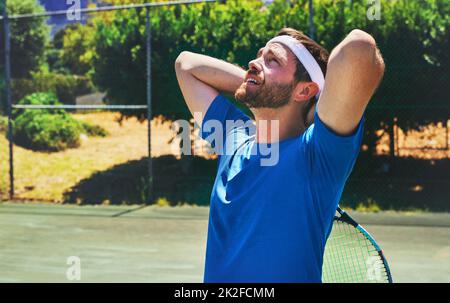 Im starting to feel the pressure. Cropped shot of a handsome young man standing alone on a tennis court during the day. Stock Photo
