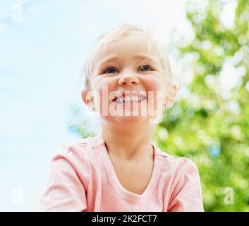 Fun under the summer sun. Shot of a cute little girl smiling while playing outside. Stock Photo