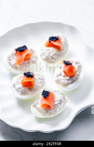 boiled eggs filled with tuna fish spread and smoked salmon and  black caviar on the top Stock Photo