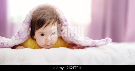 Cute little baby lying under pink blanket. Stock Photo