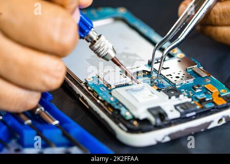 Technician repairing inside of mobile phone by soldering iron. Integrated Circuit. the concept of data, hardware, technology. Stock Photo