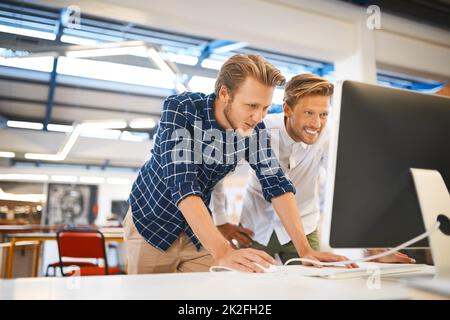 Working side by side. Cropped shot of two young male designers working on a desktop in their office. Stock Photo