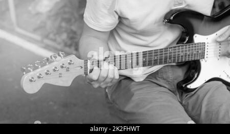 Black and white photo of a young guy playing guitar, close-up, focus on fingers Stock Photo