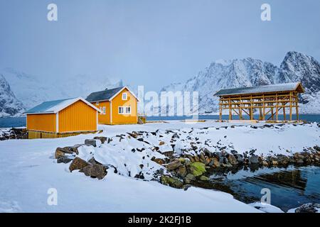 Rorbu house and drying flakes for stockfish cod fish in winter. Lofoten islands, Norway Stock Photo