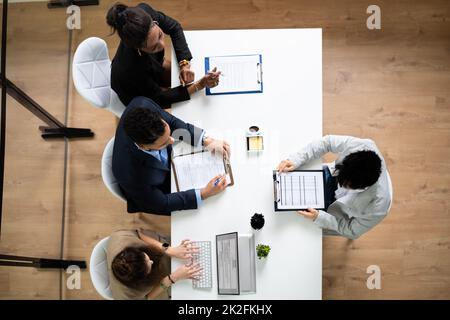 Group Of Businesspeople Interviewing A Young Male Candidate Stock Photo