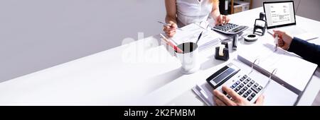 Businesspeople Calculating Invoice With Calculator Stock Photo