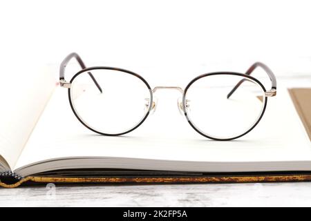 Stylish eyesight glasses and opened notebook on white wooden table Stock Photo