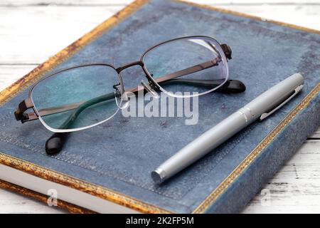 Stylish eyesight glasses and diary book on white wooden table Stock Photo