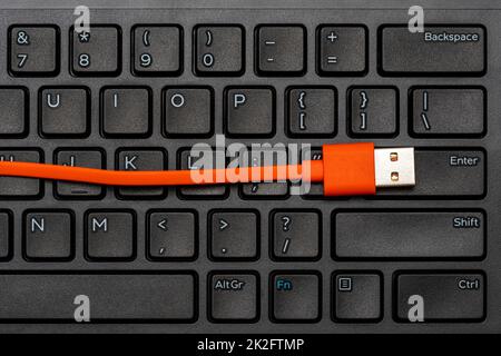 Computer keyboard and orange USB cable Stock Photo