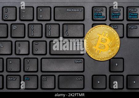 Golden Bitcoin coin on a black keyboard close-up Stock Photo