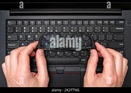 Hands holding glasses on laptop keyboard Stock Photo