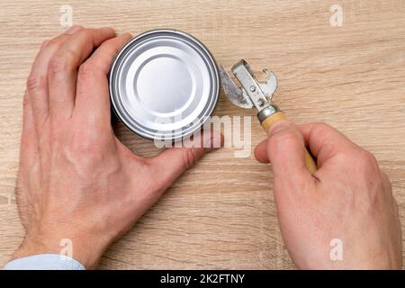 Man opening a can with a can opener Stock Photo