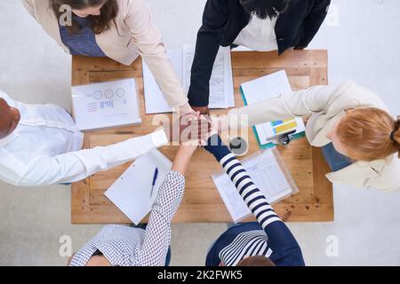 Lets do this. High angle shot of a group of colleagues standing around a desk with their hands in a huddle. Stock Photo