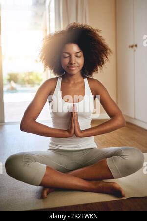 Your body will always follow your mind. Full length shot of a sporty young woman practicing yoga indoors. Stock Photo