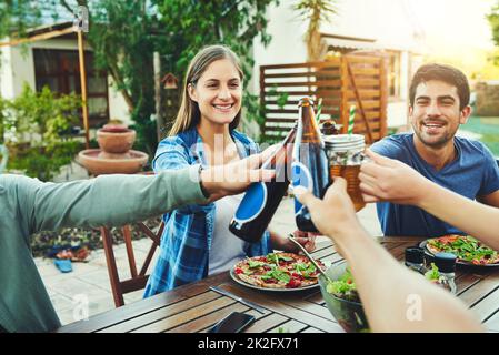Celebrate life with those you value the most. Shot of a group of young friends holding up drinks and toasting to celebrate their friendship around a table outdoors. Stock Photo