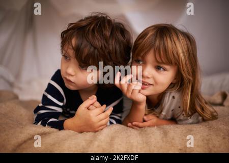 No sibling rivalry here. Shot of two adorable siblings lying underneath a fort. Stock Photo