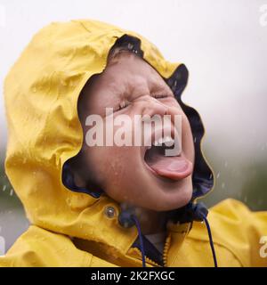 It tastes like happy. an adorable little girl playing outside in the rain. Stock Photo