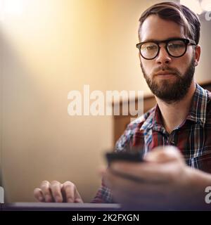 Staying connected to his contacts. a trendy young man using his cellphone. Stock Photo