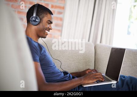 Immersed in his studies. a handsome young man using his laptop while relaxing at home. Stock Photo