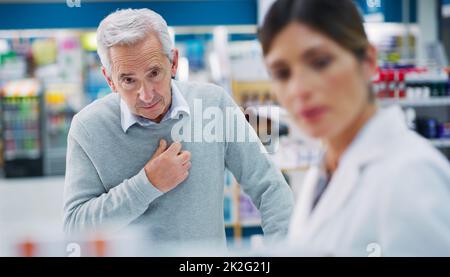 Suffering from heart disease. Shot of a pharmacist assisting a customer in a chemist. Stock Photo