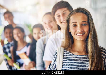 What will we learn today. Portrait of a group of happy schoolchildren standing in a line outside their classroom. Stock Photo