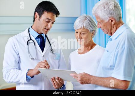 Thats completely within normal range. Shot of a handsome young doctor explaining results to a senior couple. Stock Photo
