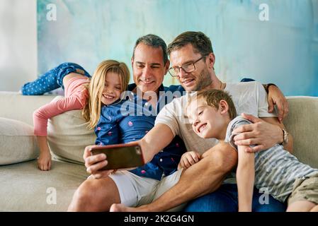 Get in here, were taking a selfie. Cropped shot of an affectionate family of four taking selfies on the sofa at home. Stock Photo