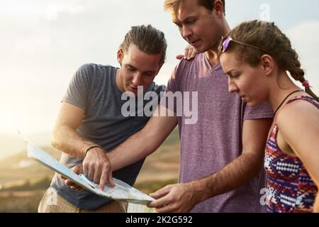 Where to wander next. Shot of three young hikers consulting a map while exploring a new trail. Stock Photo