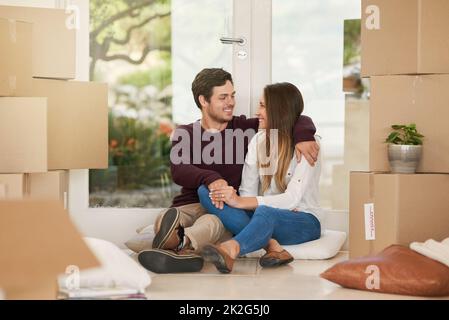 All thats left is the unpacking. Shot of an affectionate young couple taking a break while moving into a new home. Stock Photo