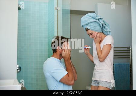 Surprise Youre going to be a dad. Shot of a young couple looking happy after taking a pregnancy test in the bathroom. Stock Photo