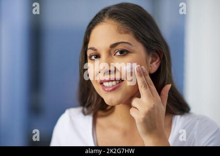 This is how I keep my skin soft and supple. Shot of an attractive young woman getting ready in her bathroom. Stock Photo