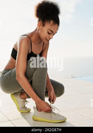 Stepping up to fitness. Shot of a sporty young woman tying her laces outside. Stock Photo